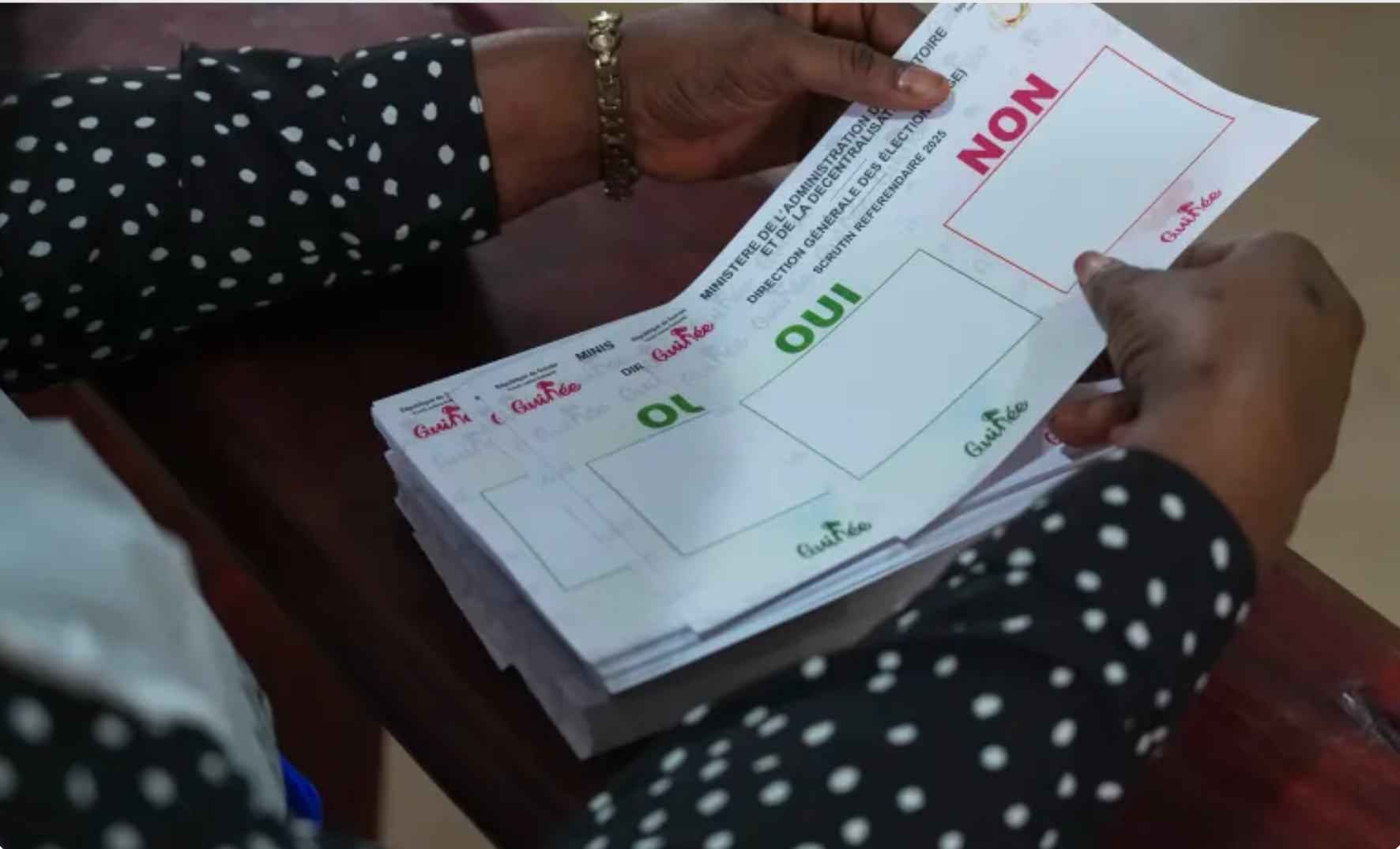A polling official holds referendum ballots at a polling station in Conakry, Guinea [Misper Apawu/AP]