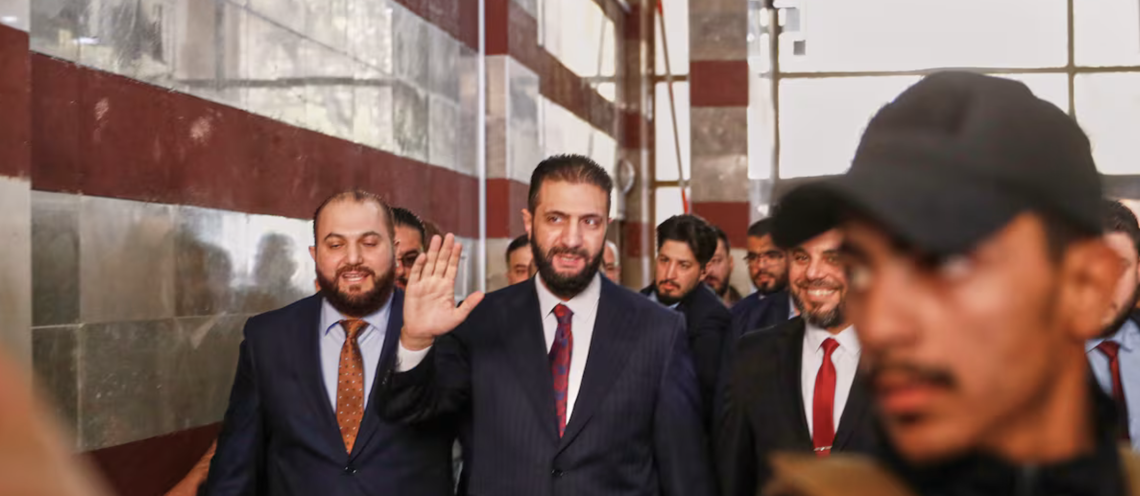 El presidente interino sirio, Ahmed al Shara, saluda este domingo al entrar en un colegio electoral en Damasco.