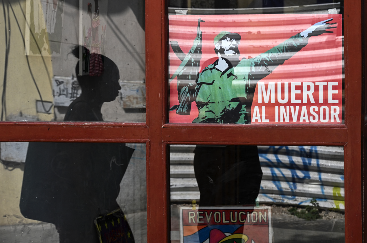 A woman walks past a poster of late Cuban leader Fidel Castro reading, “Death to the invader” in Havana, on March 13, 2026.