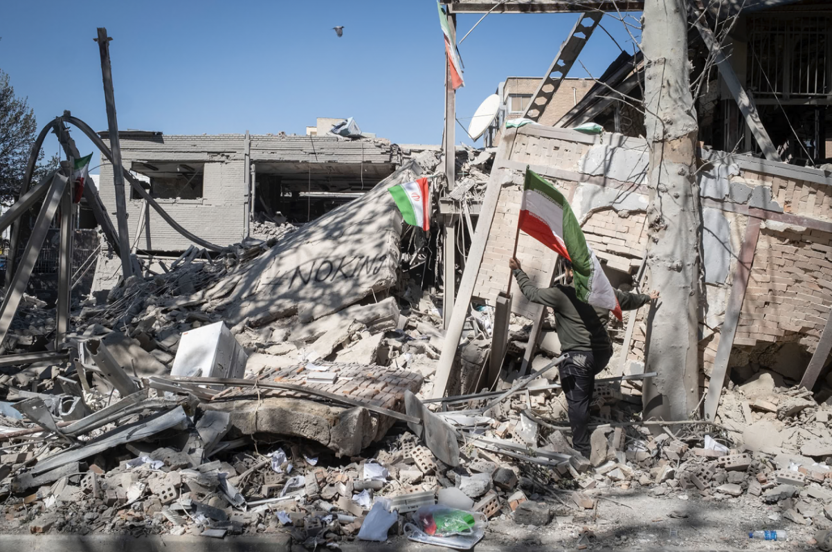 An unidentified man places a national flag on the ruins of the Sharif University of Technology’s data center, which was struck on April 6 during ongoing military operations in Tehran, Iran, on April 7, 2026