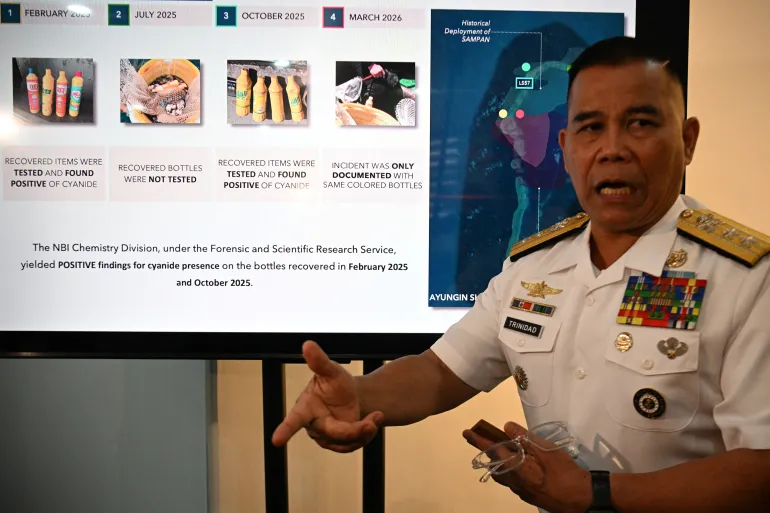 Philippine Navy spokesman Rear Admiral Roy Vincent Trinidad speaks next to a slide presentation of seized yellow bottles suspected to contain cyanide in the disputed South China Sea