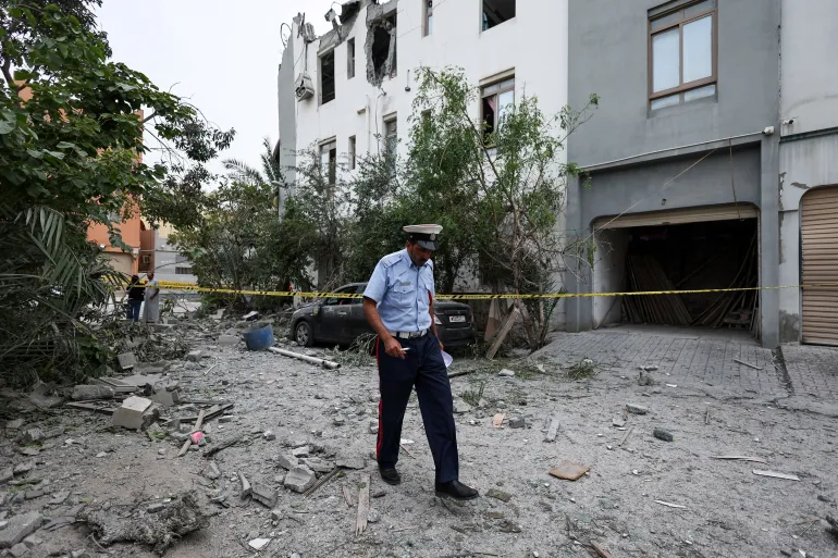 A police officer walks past a cordon tape near damaged buildings in Sitra, Bahrain, on April 4, 2026
