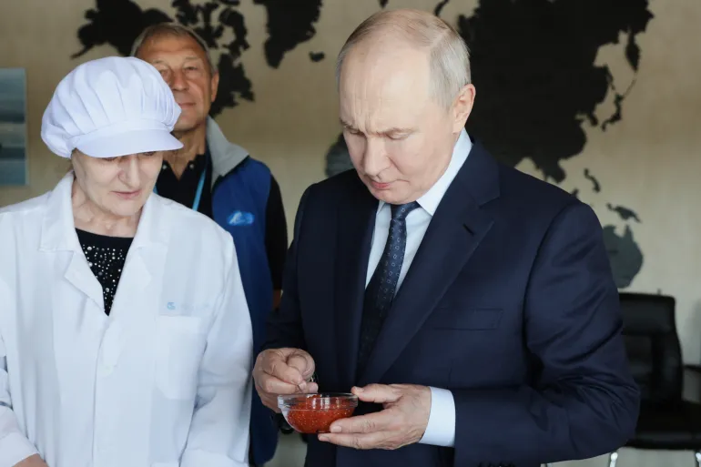 Russian President Vladimir Putin, right, tastes products as he visits a fish processing complex on Iturup Island, the largest of the Kuril Islands of Russia's far east, on Thursday, August 13, 2026